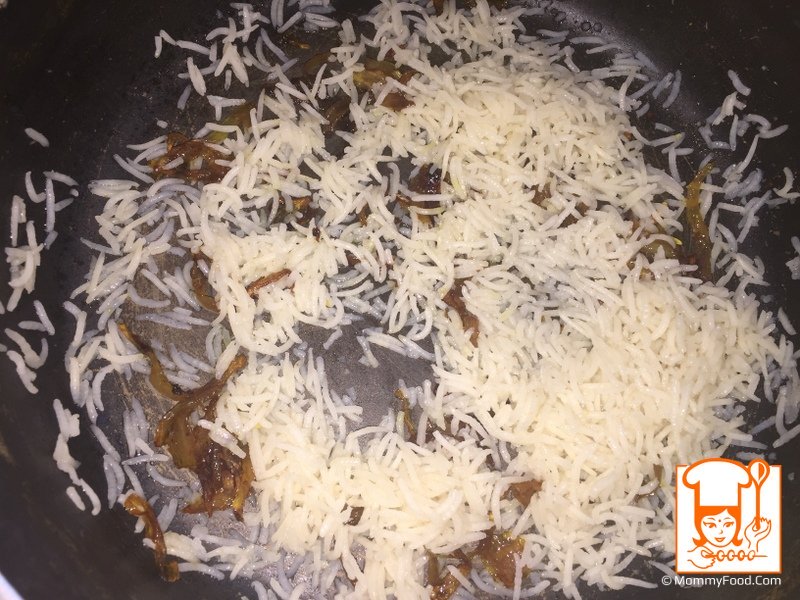 In a flat wide deep pan, layer little rice and fried onion slices